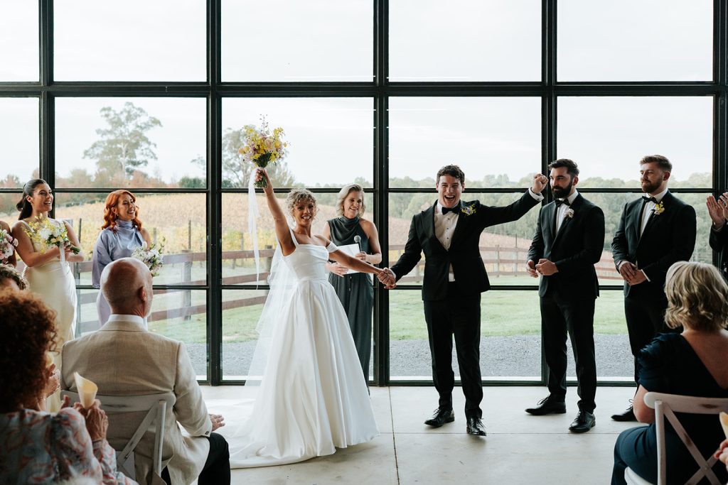 Bride and groom standing together in indoor ceremony location at their winter wedding at Yarra Ranges Estate, with vineyard views in the background